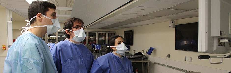 Students check a monitor while wearing their surgical masks. 